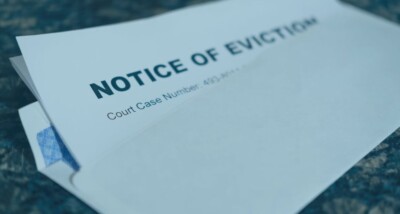 Close‑up of a formal ‘Notice of Eviction’ letter partly visible inside an envelope on a table