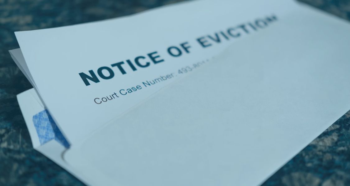 Close‑up of a formal ‘Notice of Eviction’ letter partly visible inside an envelope on a table
