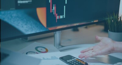 Business owner reviewing volatile financial charts and calculator on a desk, illustrating the risk of earn-out manipulation in M&A deals