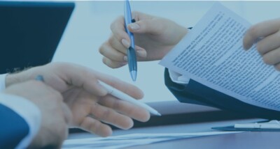 Business professionals reviewing and negotiating a written contract document at a desk.