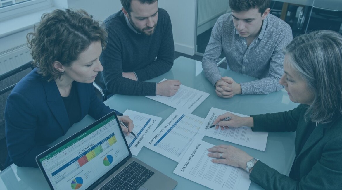Founders reviewing legal mistakes to avoid in a down round funding round Down round term sheet and cap table being reviewed before investment Start-up founders checking investor rights and dilution before a down round